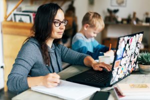 Woman working from home and child in virtual school during covid