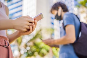 Woman texting with masked man in background